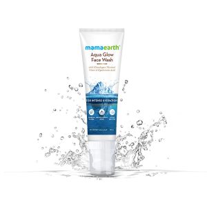 Mamaearth Aqua Glow Face Wash tube (100 ml) standing upright against a white background with dynamic water splash effects. The packaging highlights key ingredients like Himalayan Thermal Water and Hyaluronic Acid, and mentions it is paraben & SLS-free, dermatologically tested, and suitable for all skin types. Designed for intense hydration.