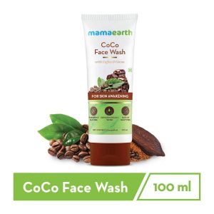 Mamaearth CoCo Face Wash tube (100 ml) placed against a white background with cocoa beans, chocolate, coffee beans, and green leaves. The product highlights ingredients like Coffee and Cocoa, and is labeled as Paraben & SLS-free, dermatologically tested, and suitable for all skin types. The tagline "For Skin Awakening" is prominently featured.